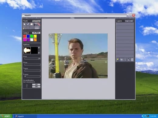 AlamDV running on Windows XP: a small effects application with a tool palette, a colour picker and a layers list, showing a video frame of a man on a sports field with a yellow lightsaber blade drawn over it.